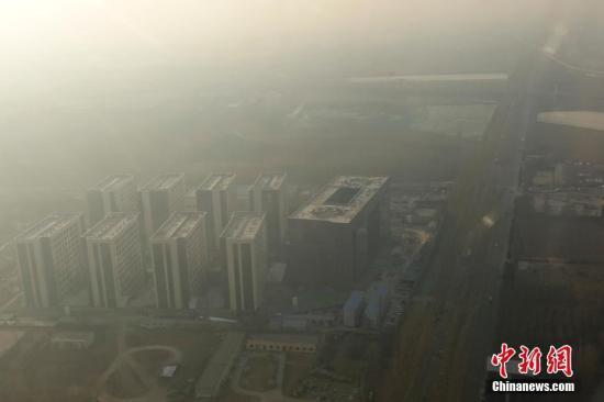 　　12月16日,，透過飛機(jī)舷窗俯瞰北京,，城市建筑隱在霧霾中。12月15日北京發(fā)布今年首個(gè)空氣重污染紅色預(yù)警：16日20時(shí),，北京市啟動(dòng)空氣重污染紅色預(yù)警,。中新社記者 盛佳鵬 攝